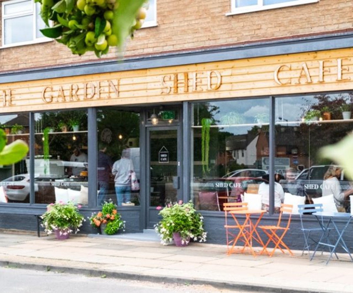 Image of the front of The Garden Shed Cafe, with pots of flowers around the door